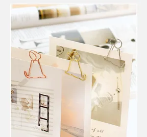 Close-up detail of cute cartoon puppy shaped metal paper clips holding stylish cards.