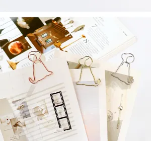 Cute puppy shaped metal paper clips detail shot, creative stationery office desk accessories.