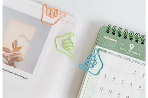Creative colorful metal paper clips in hand gesture shape, ideal for office and school use.