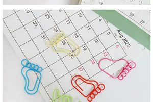 Colorful cute foot shaped metal paper clips detail shot, creative office stationery supplies.