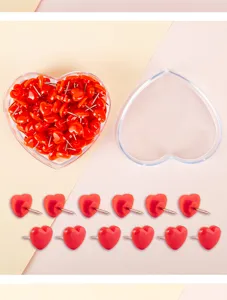 Heart-shaped pushpins detail view, red plastic tacks arranged neatly with clear storage box.