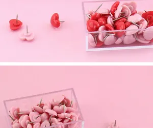 Close-up detail of cute heart-shaped pushpins in clear plastic storage box for cork board.