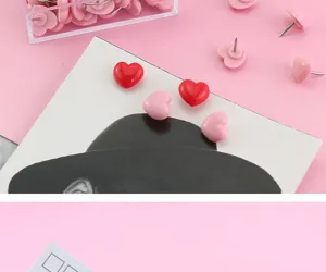 Cute heart pushpins detail shot showing pink and red plastic thumbtacks in a clear box.