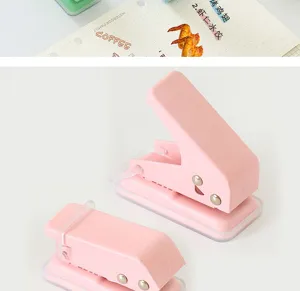 Pink manual metal mini hole puncher detail, portable loose-leaf paper binding stationery.