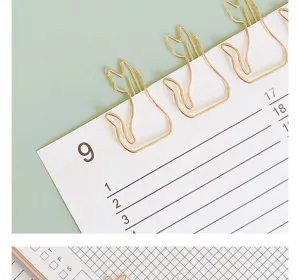Gold metal cat paper clips detail shot, cute planner bookmarks for office stationery.