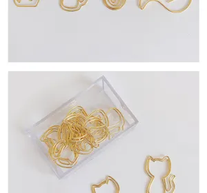 Close-up details of gold creative cute cat and various shape paper clips in clear acrylic box.