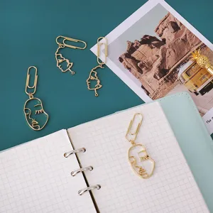 Creative gold metal abstract face paper clips, stylish minimalist bookmarks for office use.