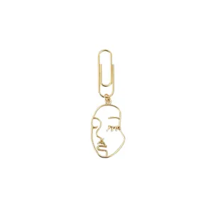 Gold metal abstract face paperclip bookmark, creative minimalist desk stationery accessory.