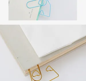Gros plan détail de jolies trombones métalliques en forme de cœur marque-page papeterie.