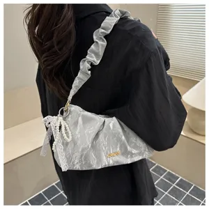 Ruched shoulder bag detail showcasing metallic crinkle texture and pearl lace pendant