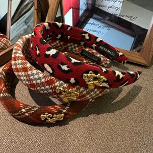 Close-up detail of woolen hairbands with red leopard print and plaid with gold horse charms.