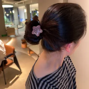 Vue détaillée d'un élastique à cheveux étoile en strass scintillant porté sur un chignon.