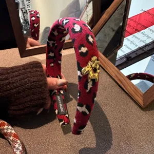 Red leopard print padded headband with elegant gold horse charm for stylish winter outfits.