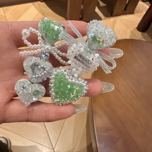 Détail en gros plan de la pince à cheveux cœur strass vert menthe perles et nœud élégants.