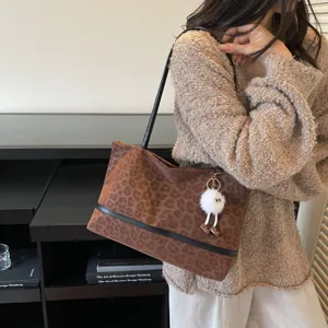 Chice braune Leo-Print-Tasche im Detail mit einem niedlichen flauschigen weißen Plüsch-Anhänger.