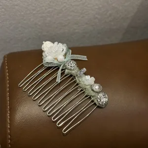 Detailed close-up of mint green hair comb decorated with rhinestone flowers and pearls.