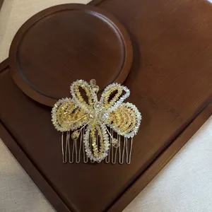 Gros plan détaillé d'un peigne à cheveux papillon en perles de cristal étincelantes sur un plateau.