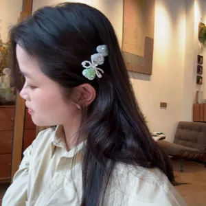 Gros plan détaillé de la pince à cheveux nœud en perles vert menthe avec strass brillants.