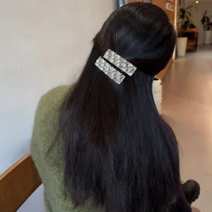 Nahaufnahme von glitzernden Strass-Haarspangen im dunklen Haar, elegante Haaraccessoires.