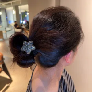 Gros plan détaillé d'un élastique à cheveux étoile en strass scintillant sur un chignon.