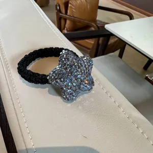 Gros plan détaillé d'un élastique à cheveux étoile en strass scintillant noir.