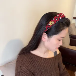 Red leopard print woolen headband with gold horse charm, showcasing winter hair accessory detail.