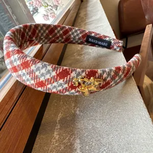 Detailed close-up of red houndstooth tweed wide headband with elegant gold horse charm.