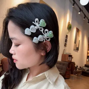 Vue détaillée de la pince à cheveux nœud cœur perle strass vert menthe sur le modèle.