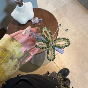 Detail shot of handmade crystal beaded butterfly hair clip, shining green and yellow rhinestones.