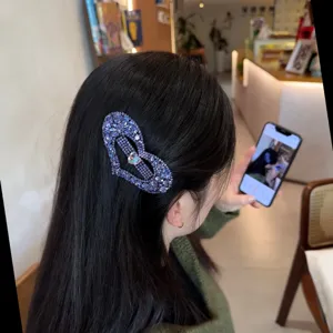 Gros plan détaillé de la pince à cheveux cœur en strass étincelant sur cheveux noirs.