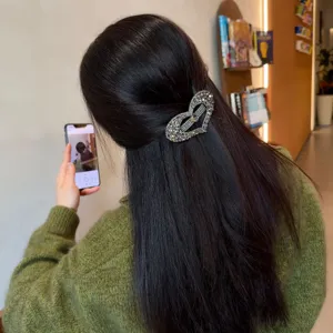Vue rapprochée de dos d'une pince à cheveux cœur en strass étincelante sur des cheveux noirs.