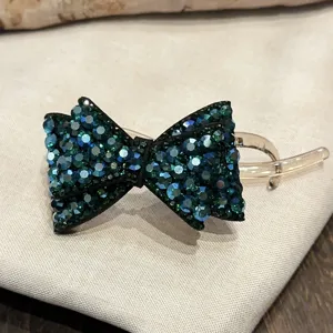 Pince à cheveux nœud strass haute couture française, accessoire élégant cristaux verts brillants.