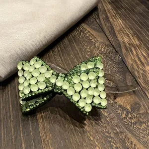 Gros plan pince à cheveux nœud strass, barrette cristal vert étincelant pour coiffure.
