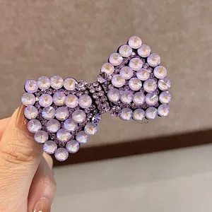 Gros plan détaillé du pince à cheveux nœud en strass violet scintillant, barrette bec de canard.