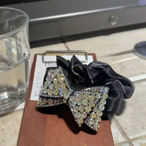 Primo piano dettagliato di un elastico per capelli con fiocco in strass e raso nero lucido.