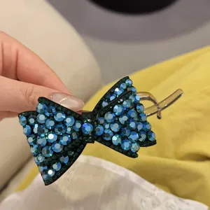 Gros plan sur la pince à cheveux nœud strass bleu montrant les cristaux scintillants et l'attache.