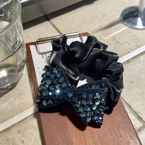 Fiocco in strass blu scuro su elastico per capelli in satin nero, ideale per acconciature.