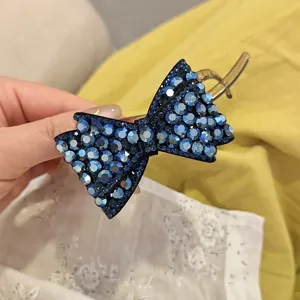 Vue detaillee d'une pince a cheveux noeud en strass bleu, eclat elegant pour coiffures.
