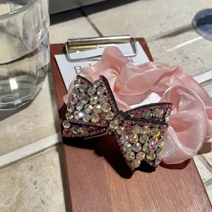 Elastico per capelli con fiocco in strass e raso rosa, accessorio elegante per coda di cavallo.