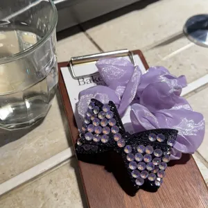 Primo piano dettagliato di un elastico in raso viola e fermaglio con strass.