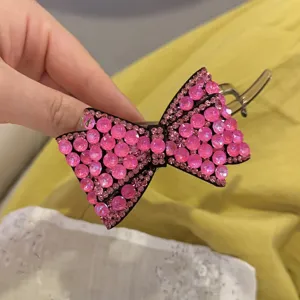 Détail de pince à cheveux nœud strass rose affichant un design scintillant et une attache robuste.