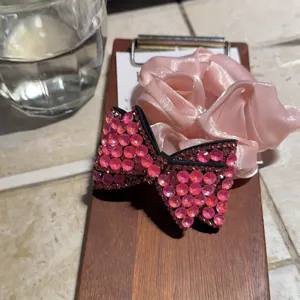 Dettaglio dell'elastico con fiocco in strass, accessorio per capelli in cristallo rosa brillante per look.