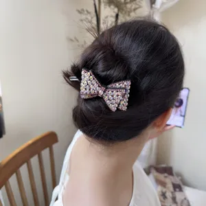 Vue détaillée de la pince à cheveux nœud en strass, accessoire étincelant pour chignon.