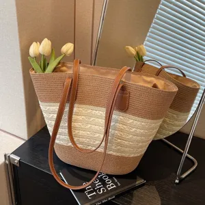 Detailaufnahme der geflochtenen Strohtasche, braun-beige Farbblock-Design mit Ledergriffen.