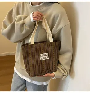 Detail view of stylish striped canvas tote bag with sturdy contrast handles and brand label.