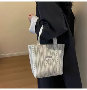 Detailed view of striped canvas tote bag detail, showing woven label and durable handles.