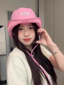 Pink bucket hat detail view, wearing display showing adjustable chin strap and fabric label.