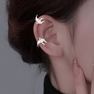 Detailed close-up showing stylish silver swallow ear cuffs worn gracefully on the ear cartilage.