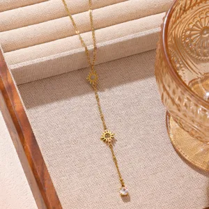 Detailansicht der filigranen goldenen Sonnen-Lariat-Halskette mit doppelten Anhängern und Kristall.