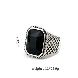 Close-up detail view of vintage stainless steel men's ring with black faceted stone and woven pattern.